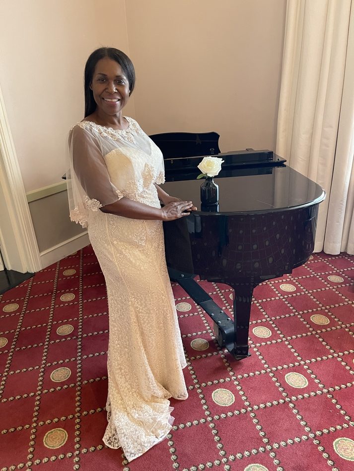 Female In White Gown Posing Next To Piano