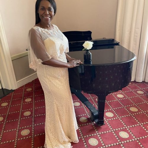 Female In White Gown Posing Next To Piano